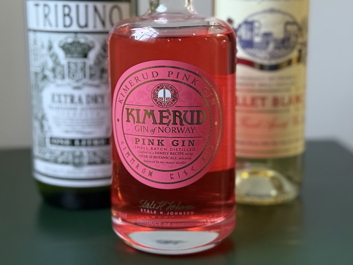 Bottle of Kimerud Pink Gin on a green table with bottles of Lillet Blanc and Tribuno Dry Vermouth nestled behind it.